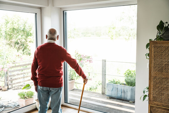 Thoughtful senior man standing in front of window