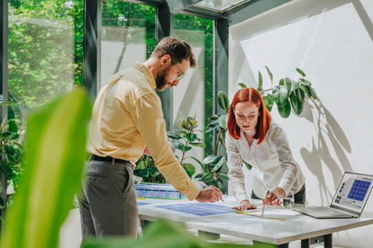Business colleagues having discussion and working on solar panel prints in office