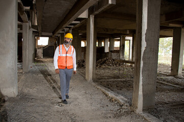 Young Indian male civil engineer or architect wearing helmet and vest holding doing inspection at construction site. Full length shot. © GAJENDRRA BHATI 