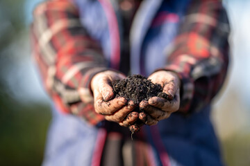 Female farmer hold soil in hands monitoring soil health on a farm