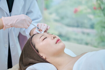 아시아 한국의 젊은 한국여성 모델이 전문병원에 치료실에서 전문의사가 주사기로 얼굴에 성형,노화방지,주름개선 또는 리프팅 시술을 받고 있다. 