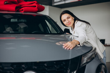 Woman hugging a new car in a car showroom
