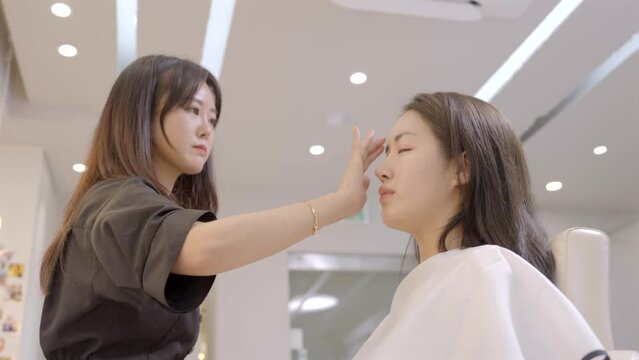 고객의 얼굴에 화장이 잘 스며들도록 손가락으로 화장을 하고있는 메이크업아티스트