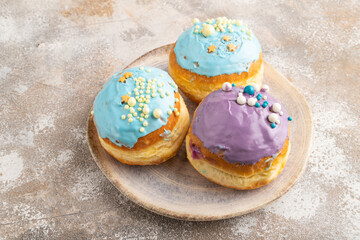 Purple and blue glazed donut on brown concrete, side view.