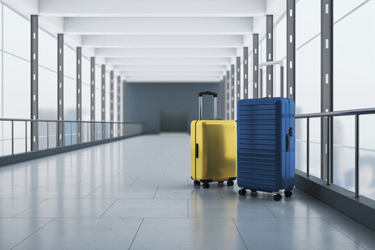 Travel, booking and vacation concept with blue and yellow suitcases on concrete floor in empty airport corridor with mat glass walls and grey entrance on background. 3D rendering
