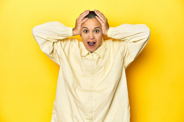 Young woman in jacket, yellow studio backdrop screaming, very excited, passionate, satisfied with something.