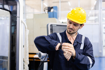 Man engineer looking watch time off work at workshop. professional male control automated machine...