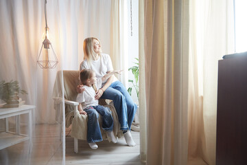 Happy loving family with mother and daughter in living room. Woman mom and small child girl playing and having convercation inside of the home - obrazy, fototapety, plakaty