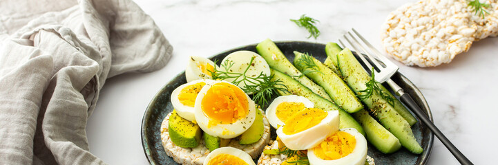 Healthy breakfasts banner, rice cakes with avocado and boiled eggs with dill and cucumber with spices, healthy wholesome food