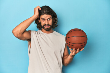 Bearded man with basketball in blue studio being shocked, she has remembered important meeting.