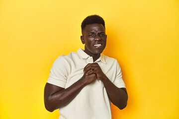 Stylish young African man on vibrant yellow studio background, scared and afraid.