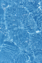 Blue water with ripples on the surface. Defocus blurred transparent blue colored clear calm water surface texture with splashes and bubbles. Water waves with shining pattern texture background.