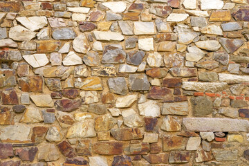 The texture of the old medieval wall of the house, lined with brown stone