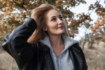 Portrait of a beautiful woman  hold the fall leaves and resting in the park. The happy girl wearing knitted sweate