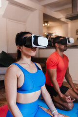 Latin couple man and woman meditating using virtual reality headsets at home in Mexico Latin America. Positive hispanic people in their apartment practising yoga using VR modern technology