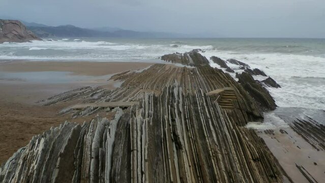 Low dolly above sharp jagged rocks at itzurun beach zumaia spain
