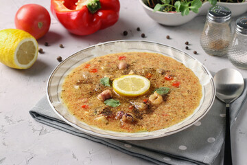 Tomato soup with seafood and egg in deep plate on light gray background