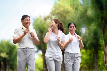 Asian Seniors and Daughter Jogging and Relaxing in the Park, Family Bonding in Nature, Seniors and Family Enjoying Exercise and Relaxation in the Green Park, Health Care and Family Bonding Concept