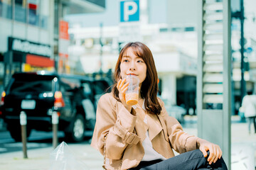 街中でアイスコーヒーを飲む日本人女性