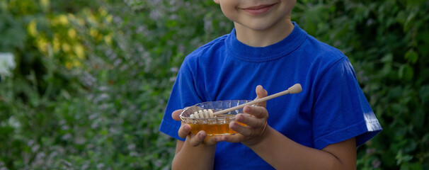 the boy eats honey in the garden, honey from his apiary. Selective focus.