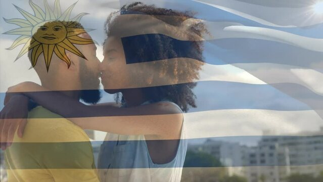 Animation of waving uruguay flag against biracial couple kissing outdoors