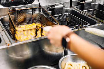 Chef cooking french fries in hot oil on kitchen