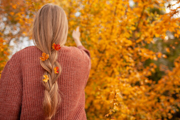 Portrait of a beautiful woman  hold the fall leaves and resting in the park. The happy girl wearing...