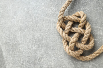 Knotted thick rope close-up on gray background. Place for text