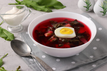 Beet soup with sorrel and egg in a white bowl