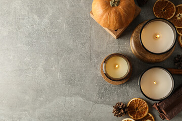 Candles, pumpkins and oranges on gray background, space for text