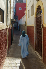 Morocco. Rabat. A women wearing veil and djellaba walk in a old street of the medina