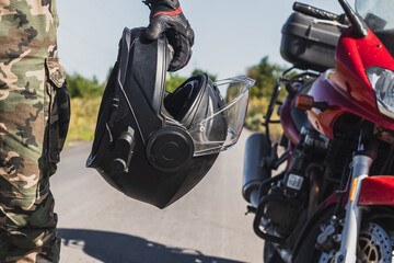 motorcycle helmet in the hand of a man on the background of a motorcycle