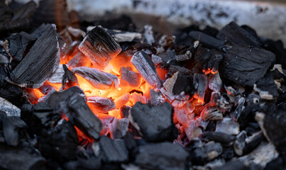 Ember of charcoal on a barbeque grill. Close-up of fire, glowing charcoal and hot embers. Summer,...