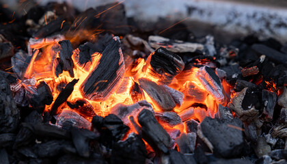 Ember of charcoal on a barbeque grill. Close-up of fire, glowing charcoal and hot embers. Summer, heat, temperature, leisure activity, outdoors, barbecue season.