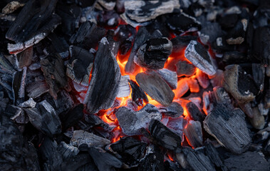 Ember of charcoal on a barbeque grill. Close-up of fire, glowing charcoal and hot embers. Summer, heat, temperature, leisure activity, outdoors, barbecue season.