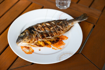 Close-up grilled gilthead fish on a plate. Barbecue, healthy sea food.