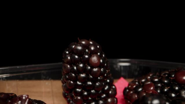 I place the blackberry back into the container on a black background. And then I close the lid. Dolly slider extreme close-up.