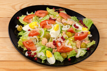Lettuce salad with tuna, boiled eggs, vegetables on black dish