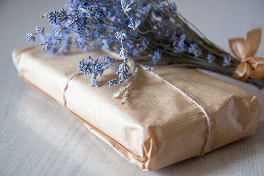 a gift in craft paper with a bouquet of lavender on the table