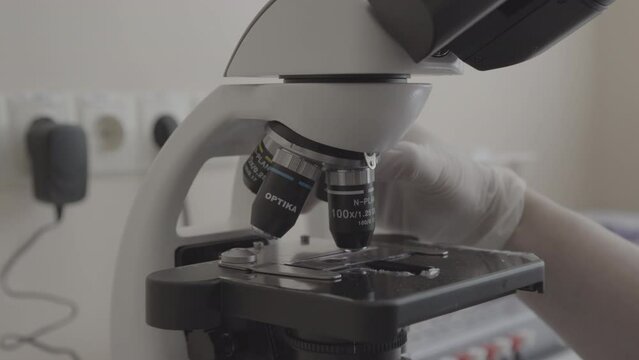 Lab technician adjusting microscope. Close-up. Lab technician working with the microscope. Modern microscope in the laboratory. Conducting research