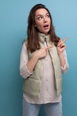 young brunette woman in a shirt and vest points a finger for ideas and inspiration on a background with copy space