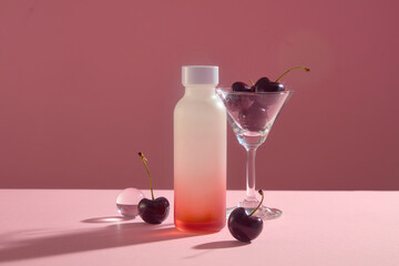 Cherries are contained inside a cocktail glass. Empty label bottle in gradient red color for branding mockup. Cherry can help slow down the aging process