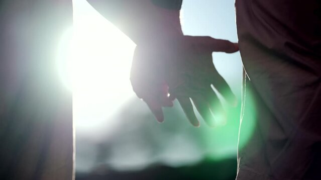 Senior couple joining hands outside in sunlight backlight flare. Older married people help and support concept