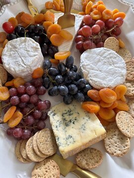 Close-up of a cheese plate with brie, stilton, camembert, grapes, crackers and dried apricots