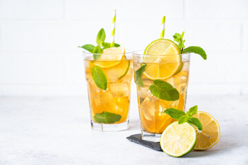 Iced tea. Black tea with lemon, lime, mint and ice. Cold lemonade, summer drink, white background.