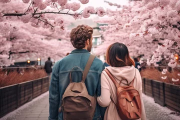 Poster rearview multiethnic couple travelling in Japan in sakura bloom season. Happy young travelers exploring in city © A Denny Syahputra