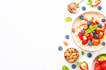 Oatmeal porrige with fresh berries and nuts on white background. Healthy breakfast, top view with...