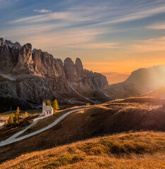 South Tyrol, Italy - The Chapel of San Maurizio (Cappella Di San Maurizio) at the Passo Gardena Pass in the Italian Dolomites at autumn with warm colorful sunset sky and clouds