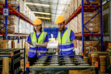 checking and inspecting metal machine part items for shipping. male and woman worker checking the store factory. industry factory warehouse. The warehouse of spare part for machinery and vehicles.