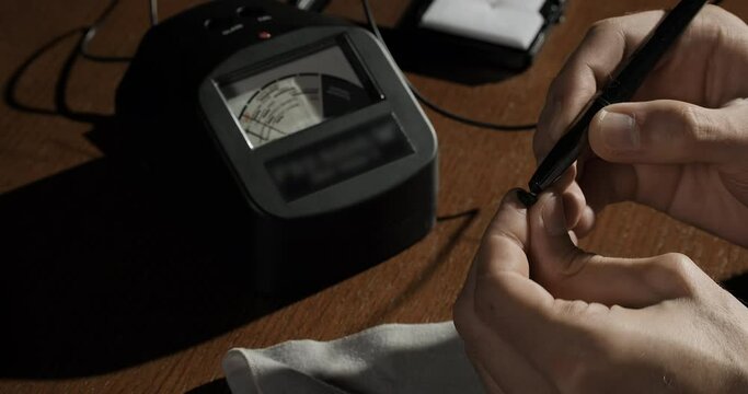 Jeweler or gemologist checking quality of gemstone with gem tester. Close-up shot